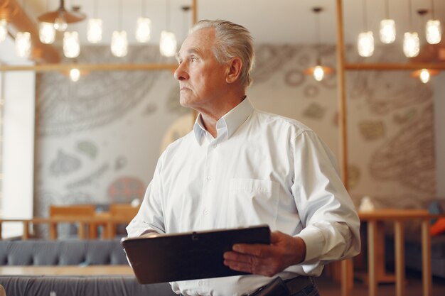 Elegante oude man in een café met behulp van een laptop