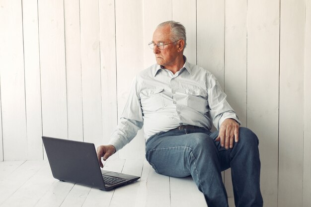 Elegante oude man om thuis te zitten en een laptop te gebruiken