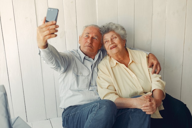 Elegante oude paar om thuis te zitten en een telefoon te gebruiken