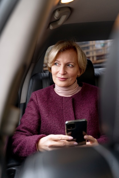 Elegante rijpe vrouw die in een taxi zit