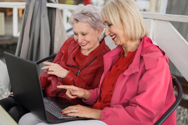 Elegante rijpe vrouwen die laptop met behulp van