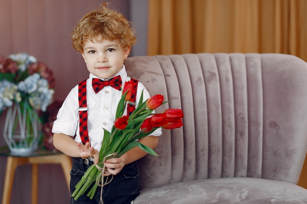 Elegante schattige kleine jongen met boeket van tulp