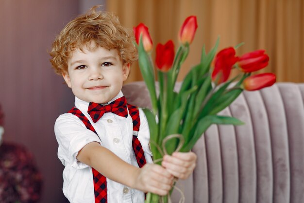 Elegante schattige kleine jongen met boeket van tulp