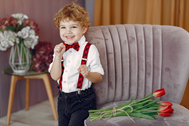 Elegante schattige kleine jongen met boeket van tulp
