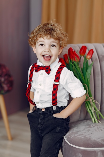 Elegante schattige kleine jongen met boeket van tulp