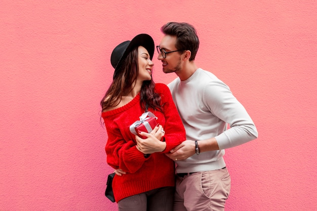 Elegante stijlvolle paar verliefd hand in hand en kijken met plezier naar elkaar. Langharige vrouw in rode gebreide trui met haar vriendje poseren.