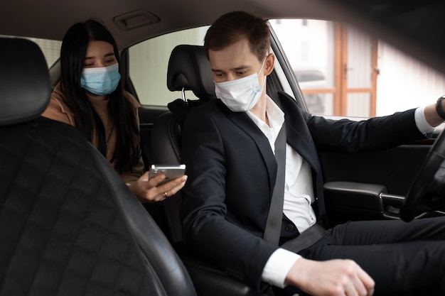 Elegante taxichauffeur en klant in een auto met medische maskers