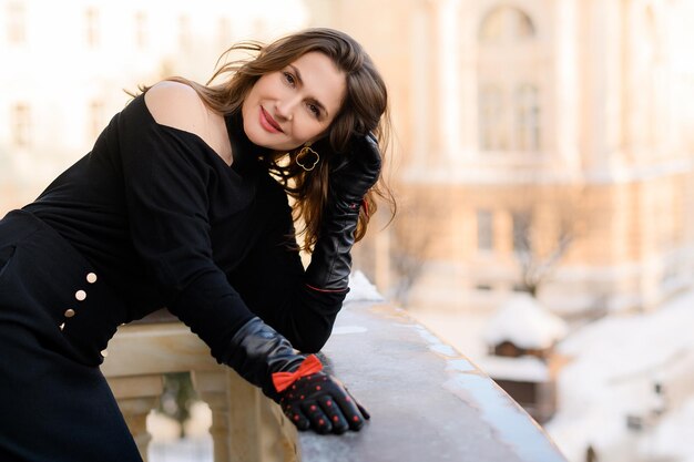 Elegante volwassen Kaukasische zakenvrouw dame poseren op het balkon Stijlvolle vrouw in zwarte modieuze kleding en handschoenen Aantrekkelijk persoon Schoonheid gezicht