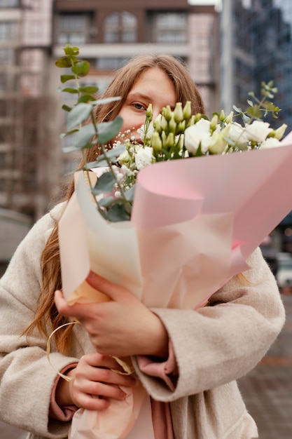 Elegante vrouw buitenshuis ruikende boeket bloemen