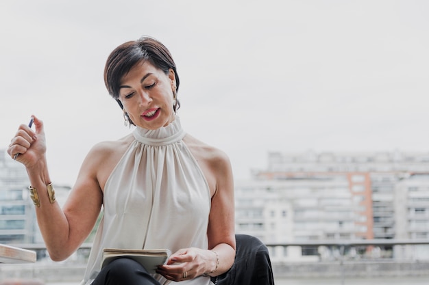 Gratis foto elegante vrouw die op het notitieboekje met copyspace kijkt