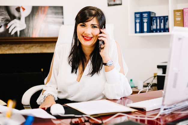 Elegante vrouw die op telefoon in bureau spreekt