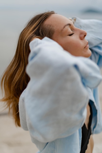 Elegante vrouw in blauwe casual outfit poseren op eenzaam strand bij bewolkt weer