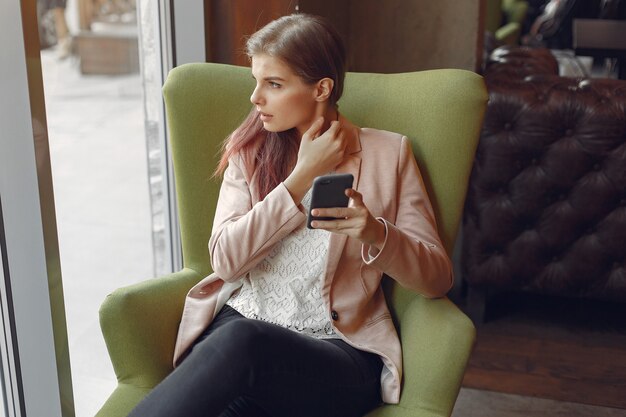 Gratis foto elegante vrouw in een roze jas tijd doorbrengen in een cafe