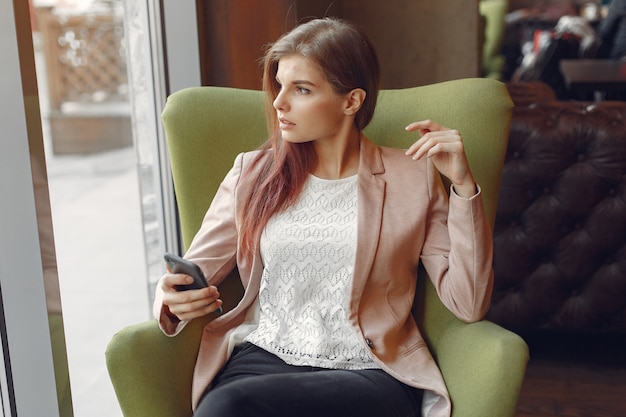 Elegante vrouw in een roze jas tijd doorbrengen in een cafe