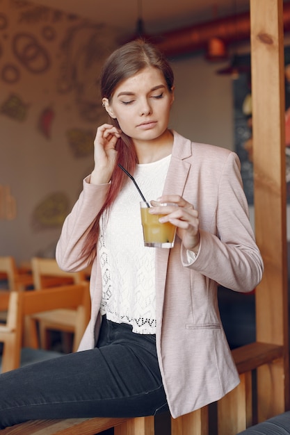 Elegante vrouw in een roze jas tijd doorbrengen in een café