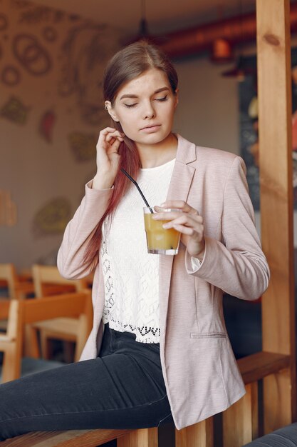 Elegante vrouw in een roze jas tijd doorbrengen in een café