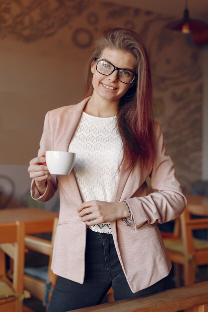 Elegante vrouw in een roze jas tijd doorbrengen in een café