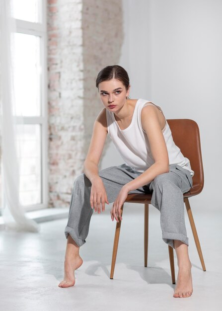 Elegante vrouwelijke model poseren in tank top en grijze broek in een lichte studio. nieuw vrouwelijkheidsconcept