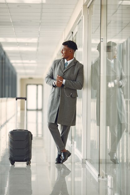 Elegante zwarte man op de luchthaven met een koffer