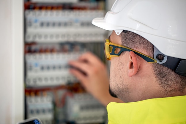 Elektrotechnicus die geconcentreerd kijkt terwijl hij in een schakelbord met zekeringen werkt