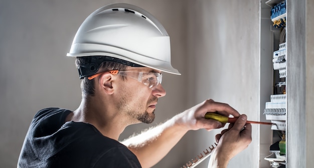 Elektrotechnicus die in een schakelbord met zekeringen werkt. Installatie en aansluiting van elektrische apparatuur.