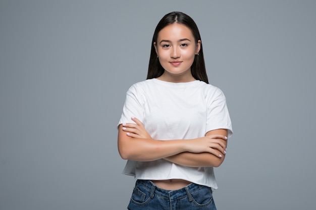 Emotie concept. Portret van boze schattige Aziatische vrouw staande poseren met gekruiste armen kijken camera met grijze kleding op een witte achtergrond