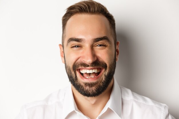 Emoties en mensenconcept. Headshot van gelukkig aantrekkelijke man lachen en glimlachen, vreugde uitdrukken