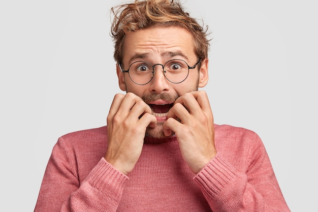 Emotionele depressieve jonge beschaamd man bijt nagels in paniek, kijkt met nerveuze uitdrukking