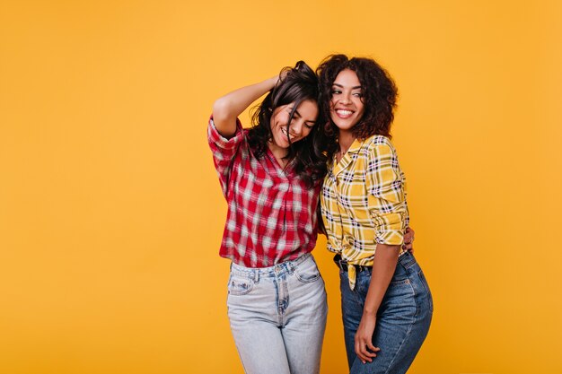 Emotionele gebruinde vrouwen poseren graag in geruite hemden. Portret van brunettes met krullend haar.