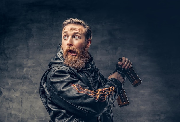 Emotionele, grappige roodharige bebaarde dronken hipster-man houdt ambachtelijk gebotteld bier vast.