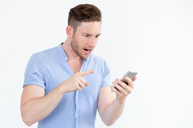 Emotionele jonge man die op smartphone huilt