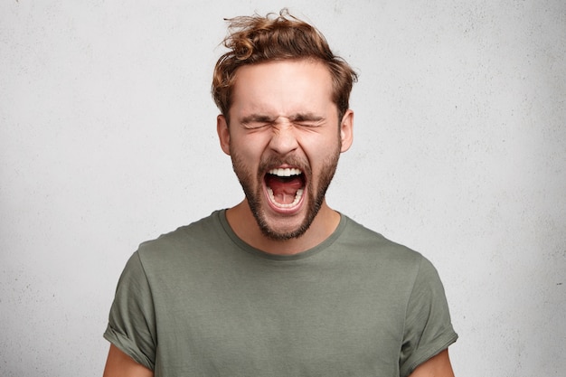 Emotionele jongere schreeuwt luid, opent zijn mond wijd, voelt zich wanhopig