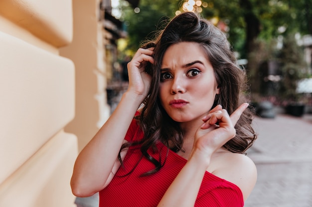 Emotionele zwartogige meisje tijd doorbrengen op straat. Jocund brunette witte vrouw poseren op stad.