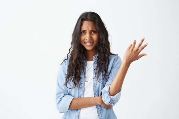 En dan. Clueless verbaasde Afro-Amerikaanse vrouw gebaart met handen in onwetendheid en verwarring, haalt haar schouders op. Negatieve gevoelens en emoties.