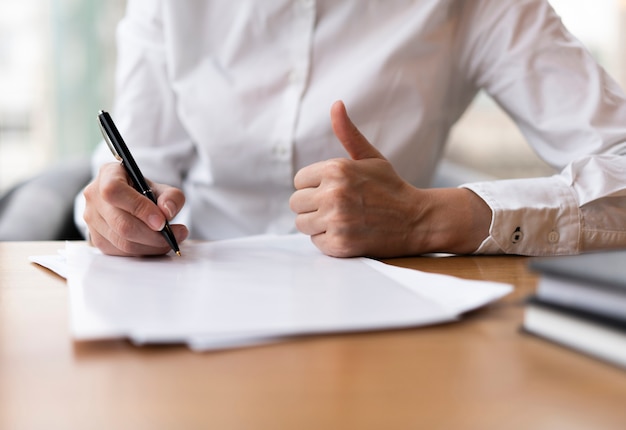 En vrouw die duimen schrijft toont