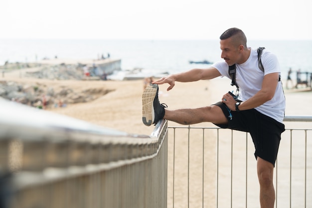 Energetische jonge atleet die met reling strekt