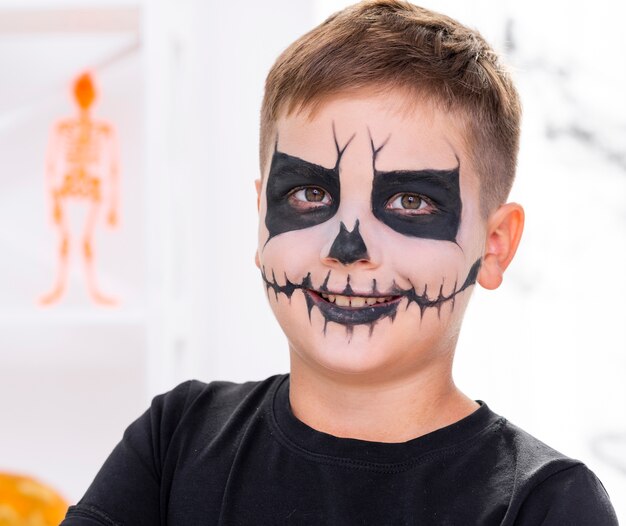 Enge jonge die jongen met gezicht voor Halloween wordt geschilderd