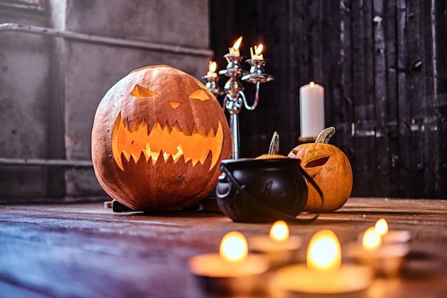 Enge pompoenen en kaarsen op een houten vloer in een oud huis. Halloween-concept.