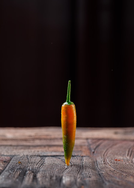 Enige rijpe peper op steentegel en zwarte achtergrond. zijaanzicht.