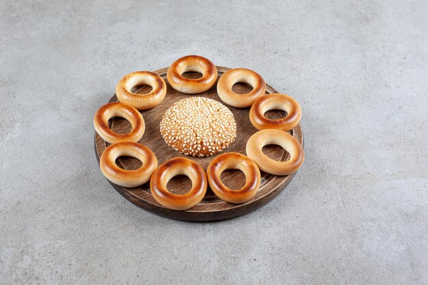 Enkel koekje omgeven door sushki op een houten bord op marmeren oppervlak.