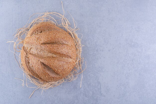 Enkele broodbrood zittend op een stapel stro op marmeren oppervlak