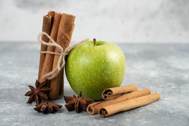 Enkele groene appel en kaneelstokjes op marmeren tafel.