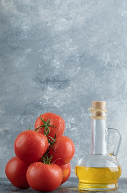 Enkele sappige tomaten met een glazen fles olie.