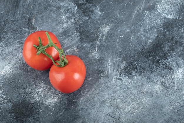 Enkele sappige tomaten op grijs.