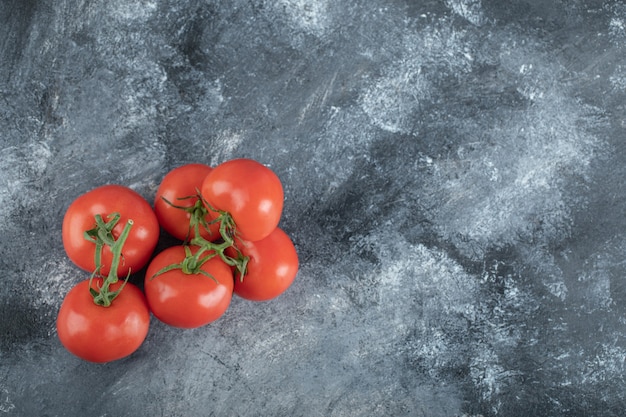 Enkele sappige tomaten op grijs.