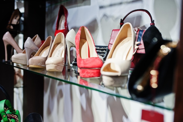 Enorme verscheidenheid aan vrouwelijke schoenen en tassen in verschillende kleuren in de schappen van de winkel