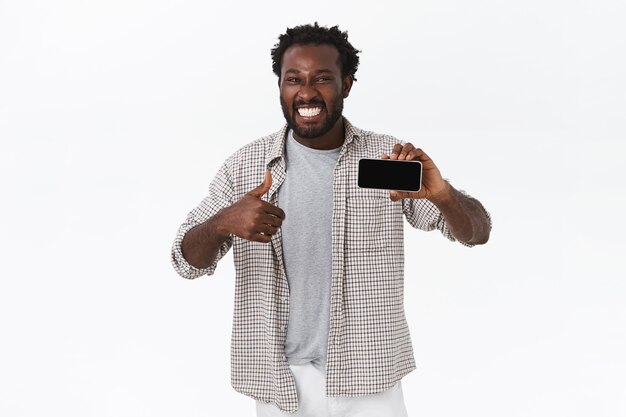 Enthousiaste lachende gelukkige Afro-Amerikaanse man verbaasd met geweldige nieuwe app