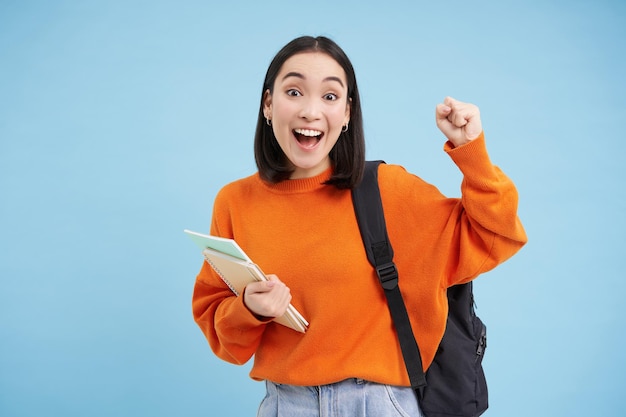 Enthousiaste studente viert het dragen van een rugzak en houdt notitieboekjes college huiswerk standi