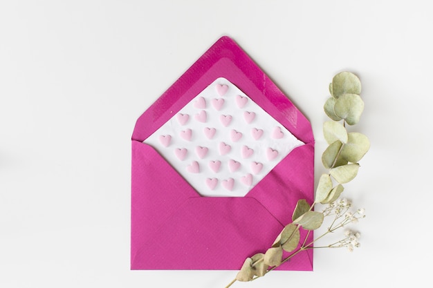 Gratis foto envelop met papier met ornament harten in de buurt van plant twijgen