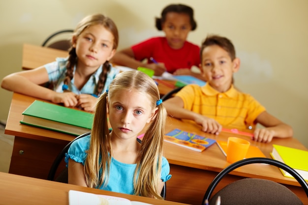 Gratis foto ernstig schoolmeisje met blauwe shirt in de klas